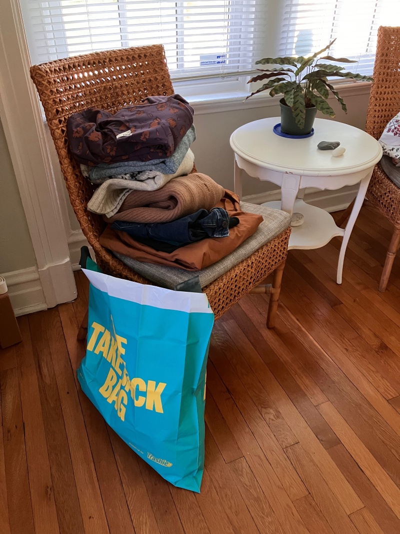 Partially filled Take Back Bag and a pile of clothes to donate 